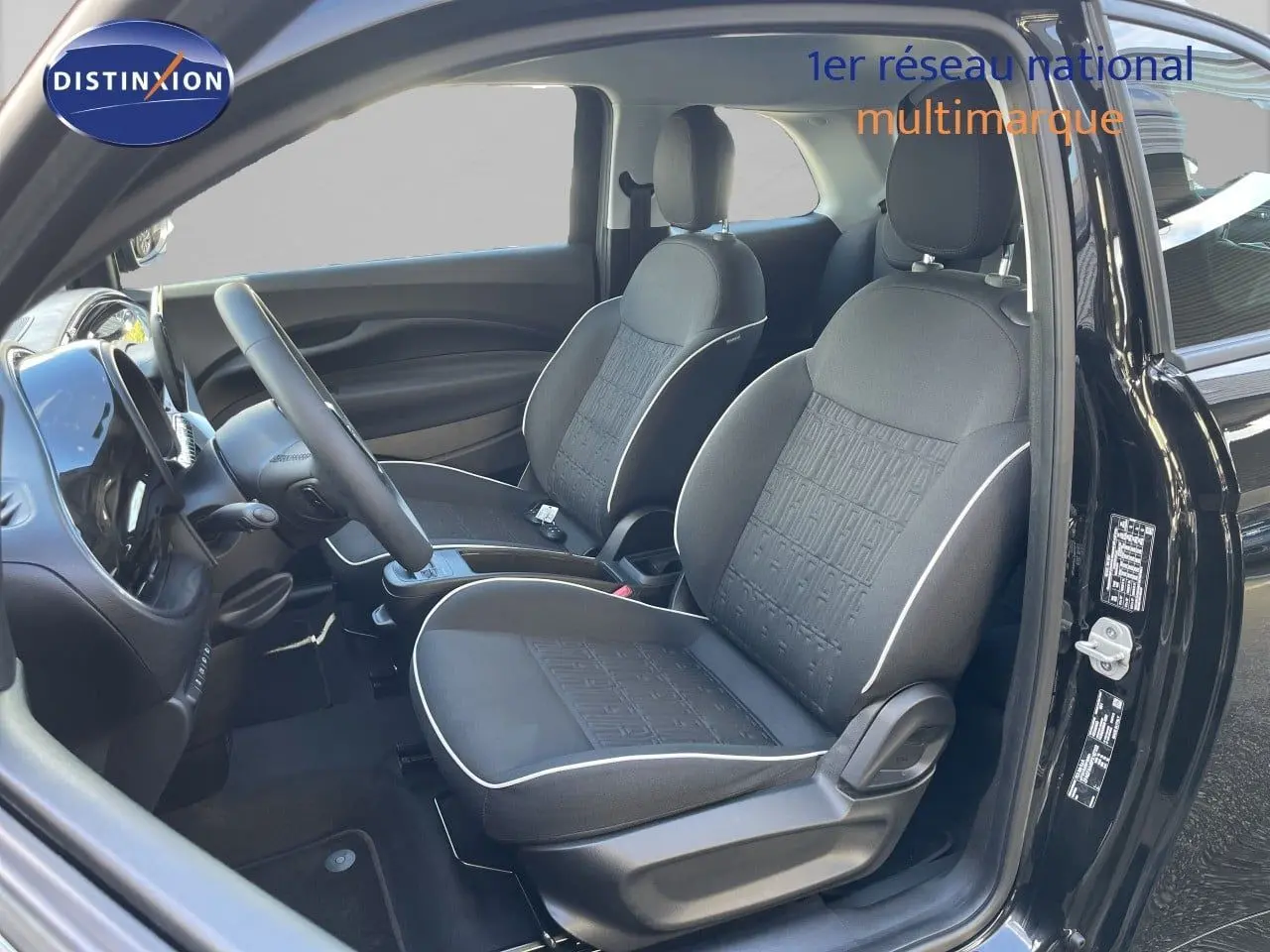 Intérieur avant droit de la Fiat 500 électrique noire Onyx 2023 avec sièges tissu noir et volant multifonction cuir.