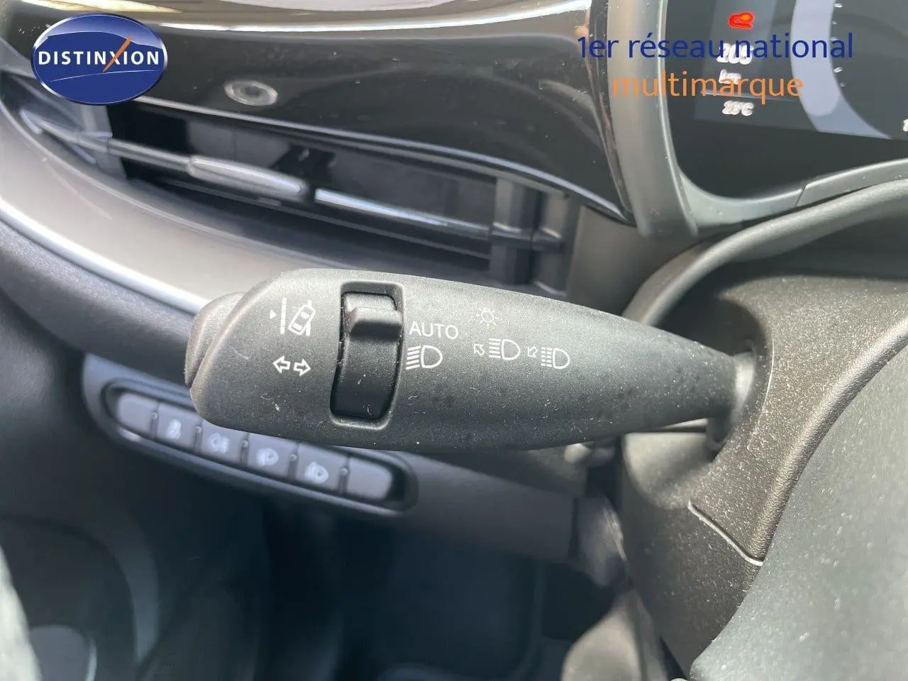 Gros plan sur la commande des feux et clignotants à gauche du volant dans l’habitacle noir d’une Fiat 500 électrique 2023.