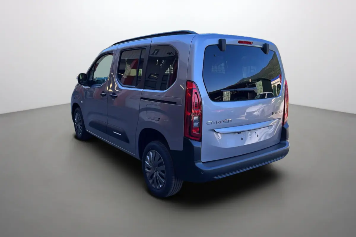 Vue 3/4 arrière gauche du Citroën Berlingo BlueHDi 100 Feel Plus gris Artense avec vitres surteintées et barres de toit.