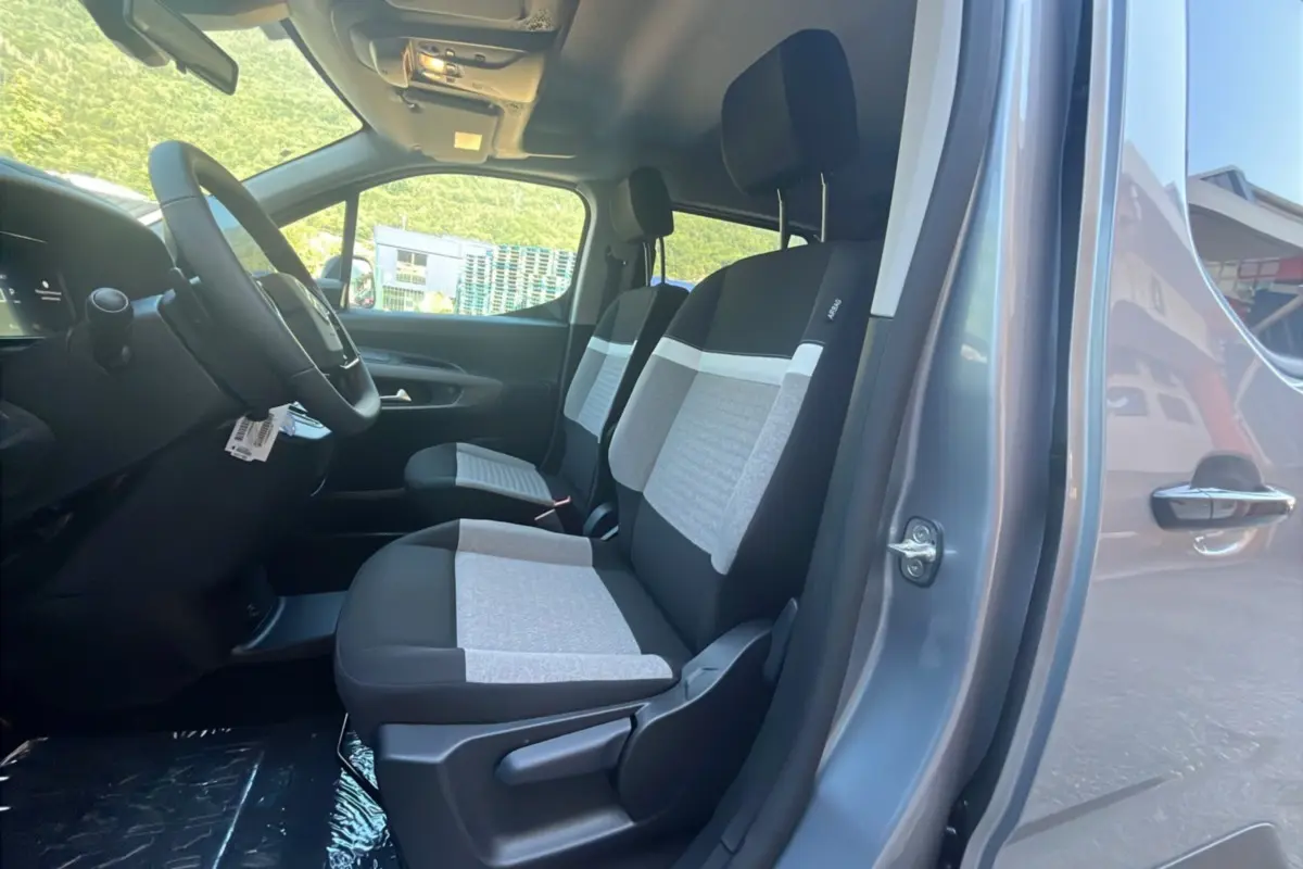 Vue intérieure côté gauche du Citroën Berlingo gris Artense, montrant les sièges avant bi-ton tissu et volant multifonctions.