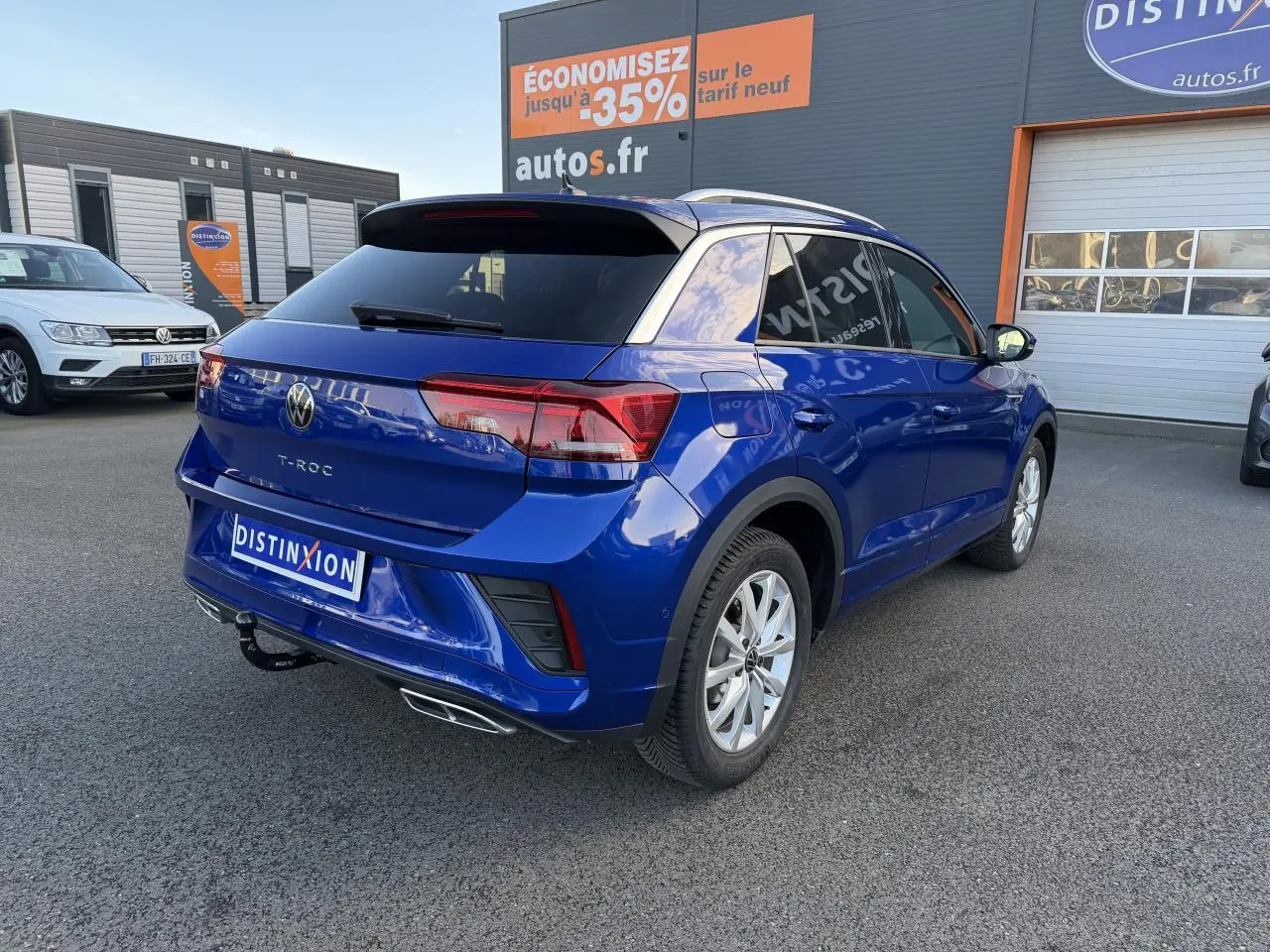 Volkswagen T-Roc bleu lapiz métallisé vu en 3/4 arrière droit avec attelage amovible et jantes alliage gris galvanisé.