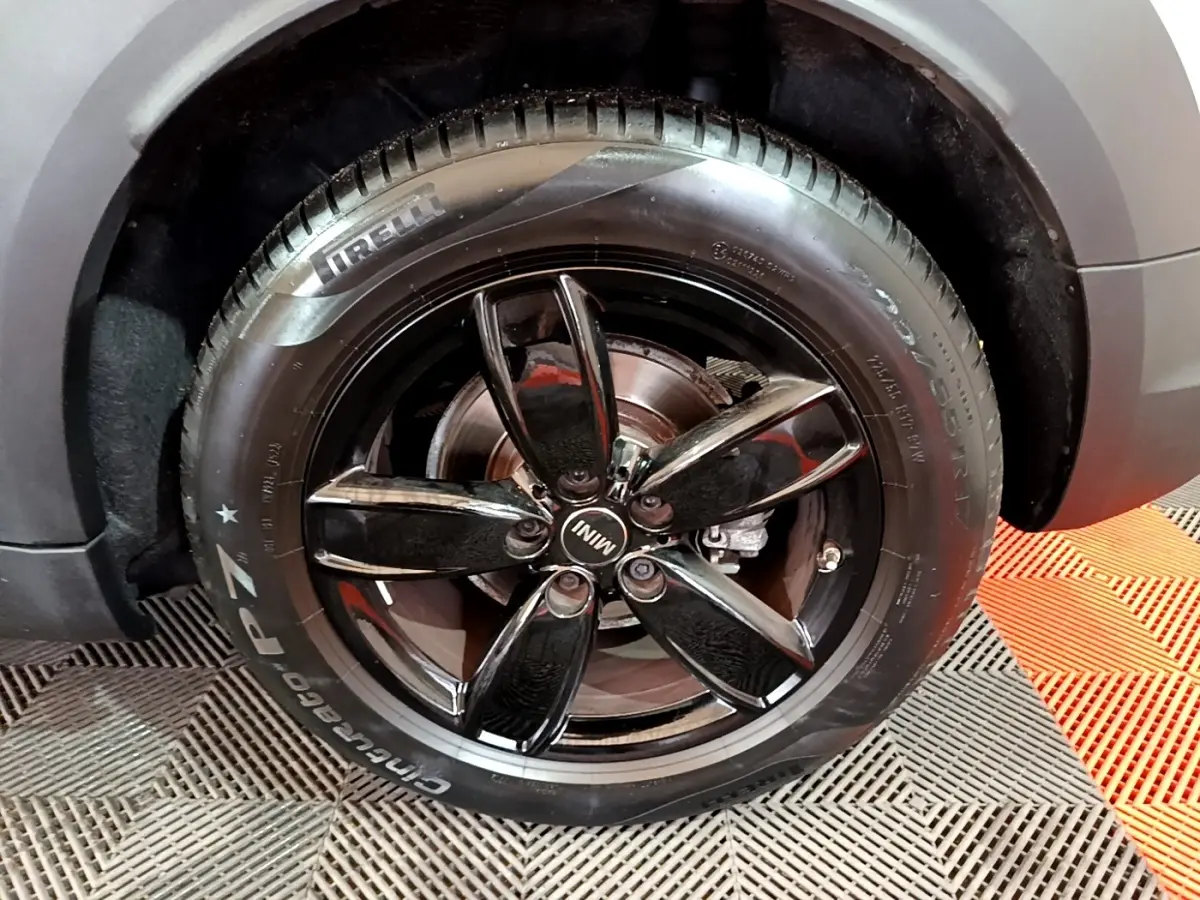 Gros plan sur la roue arrière droite d'une MINI Countryman gris clair avec jante noire brillante cinq branches.