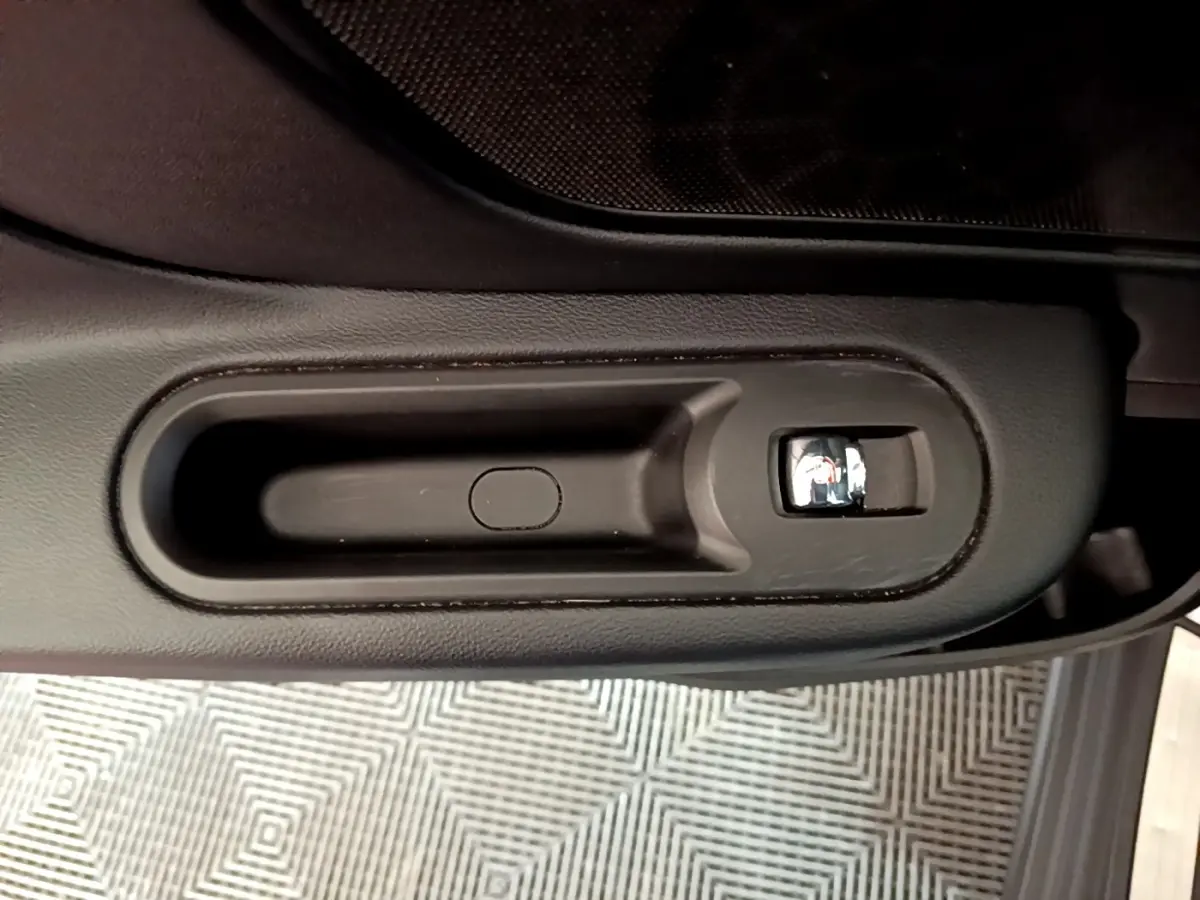 Poignée intérieure de porte noire avec bouton de verrouillage, vue en plongée dans une MINI Countryman gris clair.