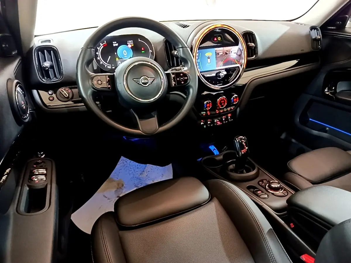 Vue intérieure avant du tableau de bord et volant noir du MINI Countryman Cooper Premium Plus 2022 avec éclairage d'ambiance bleu.