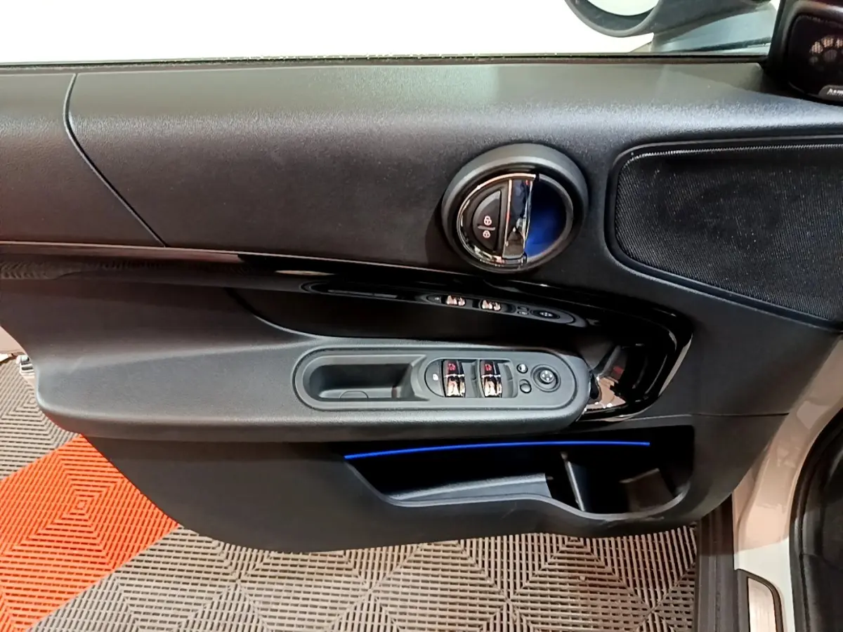 Vue rapprochée de la porte avant gauche grise d'une MINI Countryman 2022 avec éclairage d'ambiance bleu et commandes électriques.
