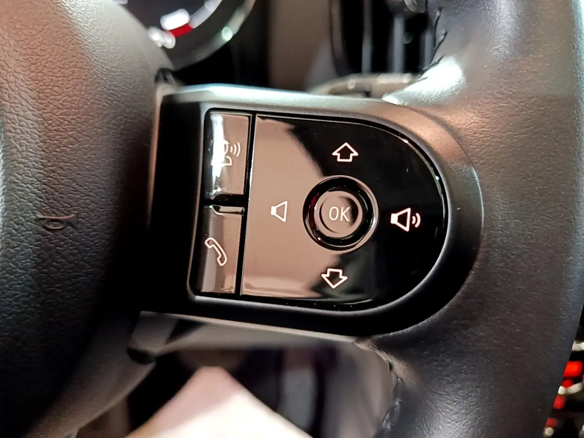 Gros plan sur les commandes noires du volant cuir du MINI Countryman gris clair, avec boutons de volume et appel.