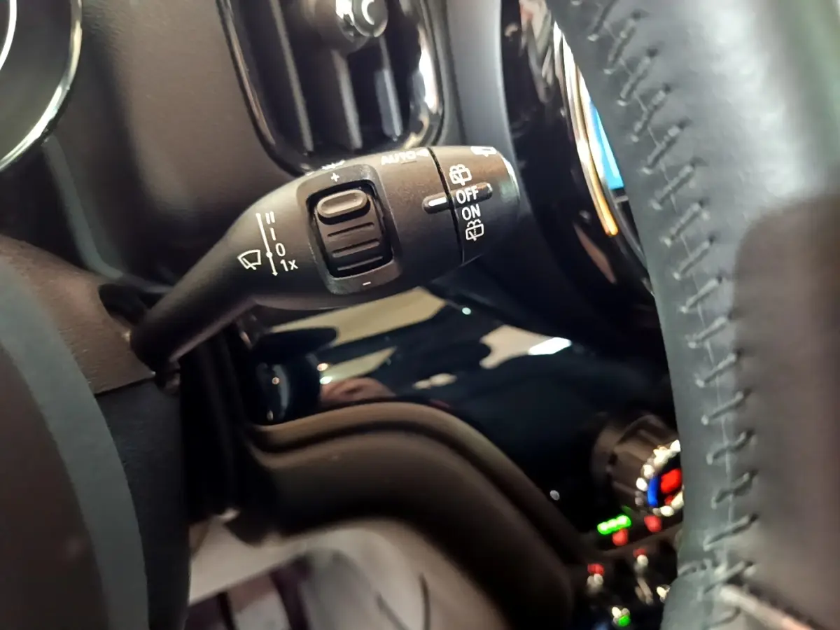 Gros plan sur la commande des essuie-glaces à gauche du volant cuir dans l’habitacle d’une MINI Countryman gris clair.