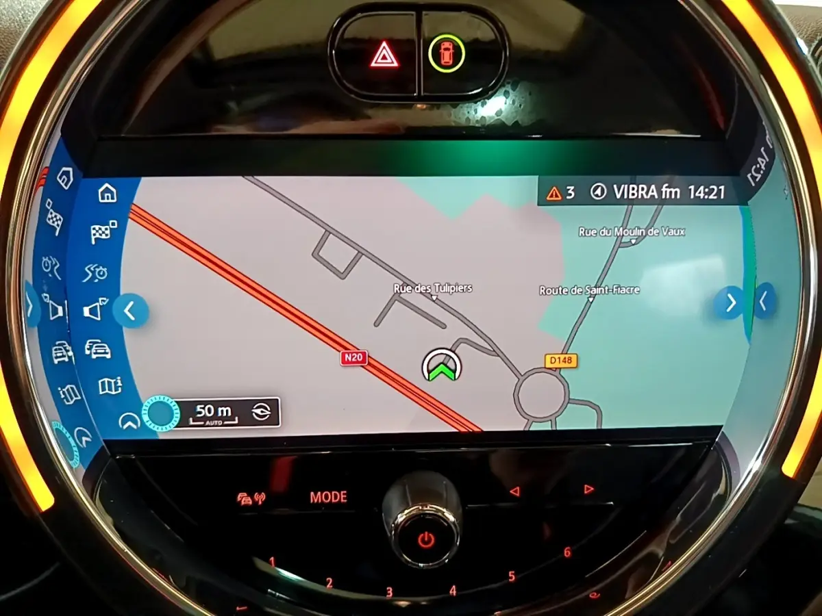 Vue rapprochée de l’écran tactile central circulaire du MINI Countryman gris clair avec navigation affichée et éclairage ambiant orange.