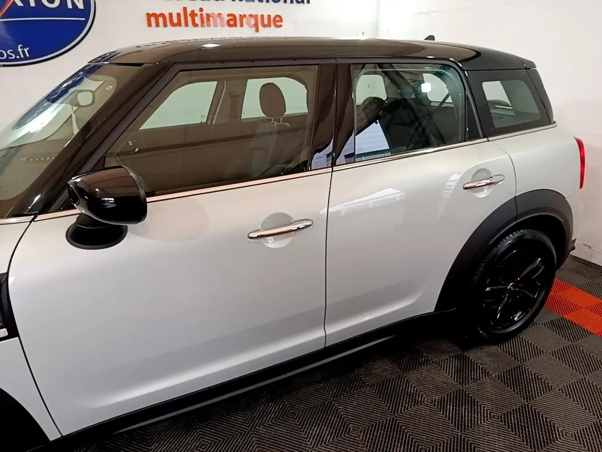 Vue latérale droite d'une MINI Countryman gris clair avec toit noir et jantes noires brillantes.