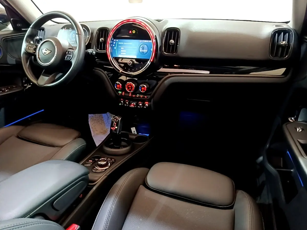 Intérieur avant du MINI Countryman Cooper gris, vue côté conducteur sur tableau de bord et éclairage d’ambiance bleu.