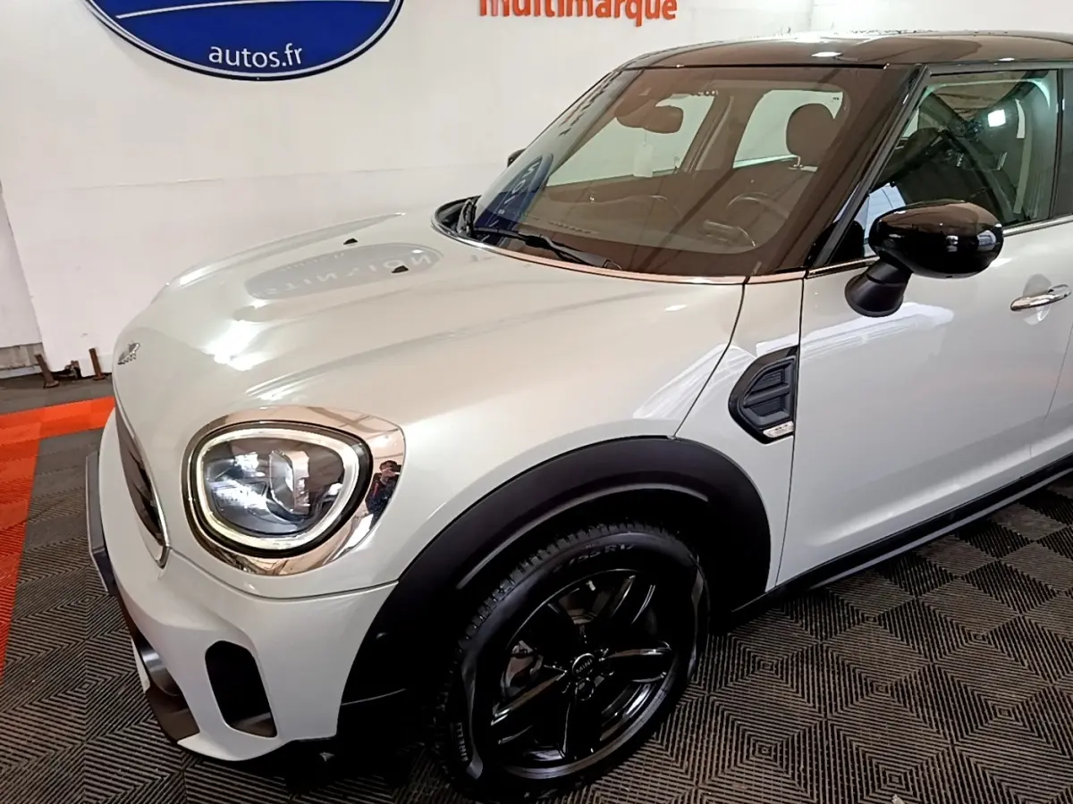 Vue 3/4 avant droit d'une MINI Countryman gris clair avec toit noir et jantes noires brillantes.