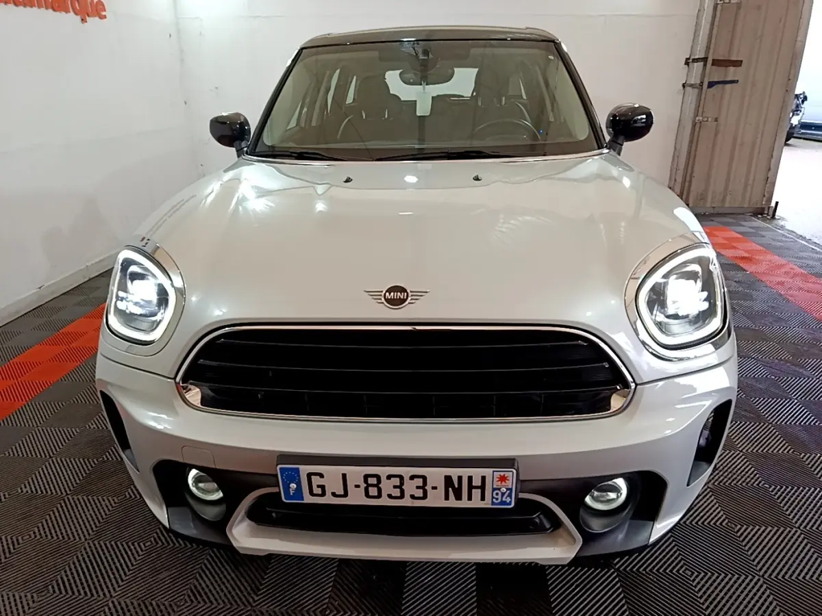Vue frontale d'une MINI Countryman gris clair avec phares LED allumés et calandre noire brillante.