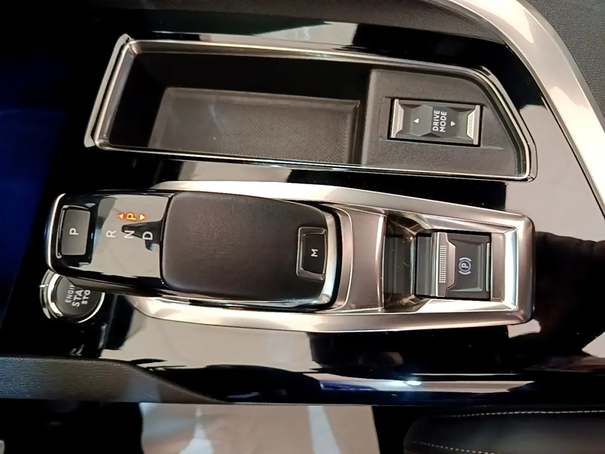Gros plan sur la console centrale noire brillante du Peugeot 3008 avec levier de vitesses automatique et bouton Drive Mode.