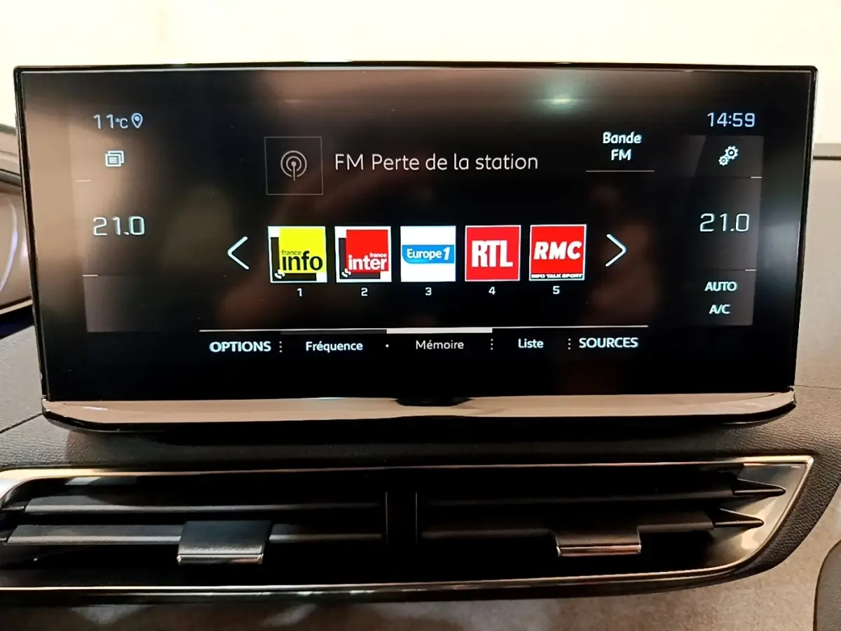 Écran tactile central affichant les stations radio dans l’habitacle d’un Peugeot 3008 noir, vue de face rapprochée.