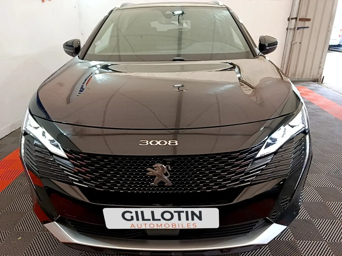 Vue avant d'un Peugeot 3008 noir 2022 avec calandre noire et phares LED allumés dans un garage.