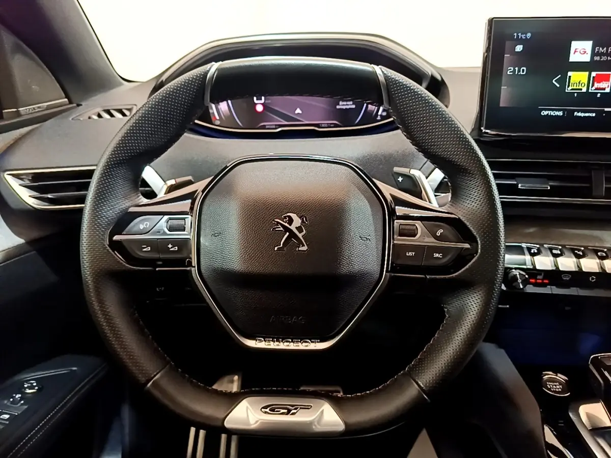 Vue intérieure centrée sur le volant cuir et alu noir du Peugeot 3008 GT Pack 2022 avec tableau de bord digital.