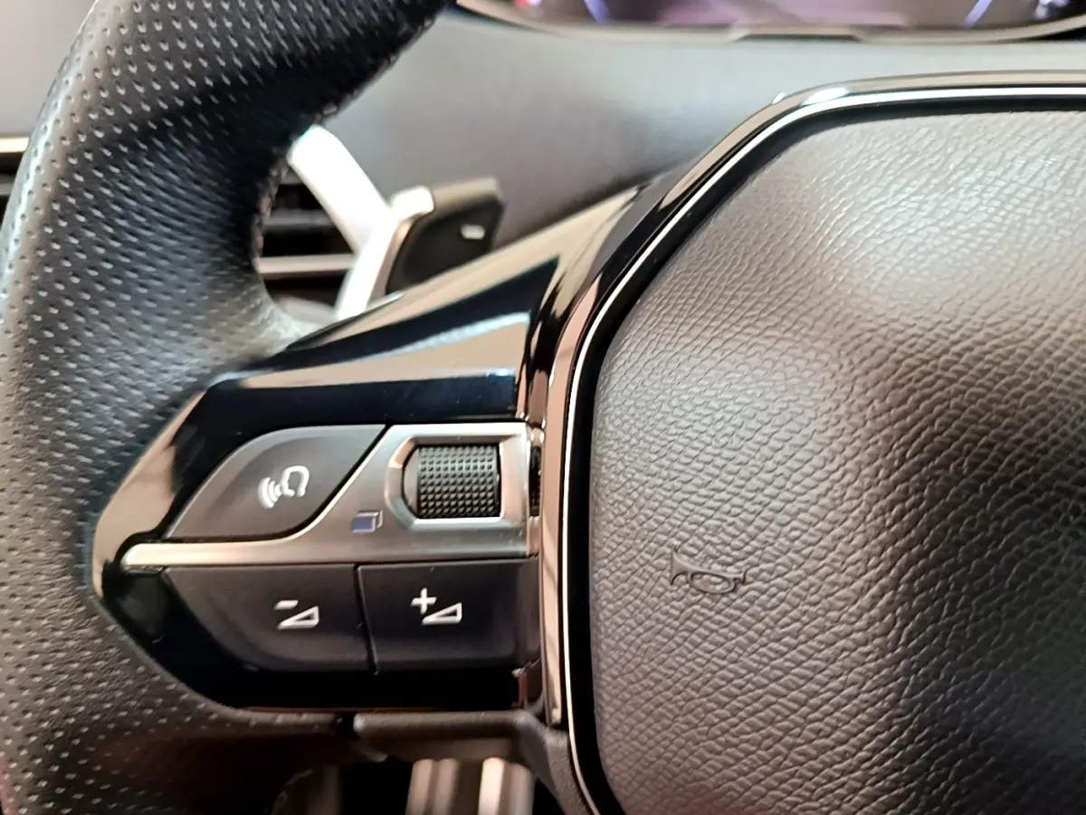 Gros plan sur le volant cuir et alu noir du Peugeot 3008 GT Pack, avec commandes multifonctions visibles à gauche.