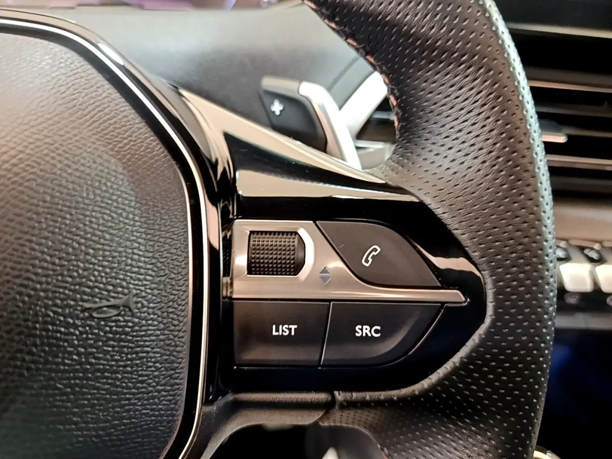 Gros plan sur le volant en cuir perforé noir du Peugeot 3008 GT Pack 2022 avec commandes multifonctions alu.