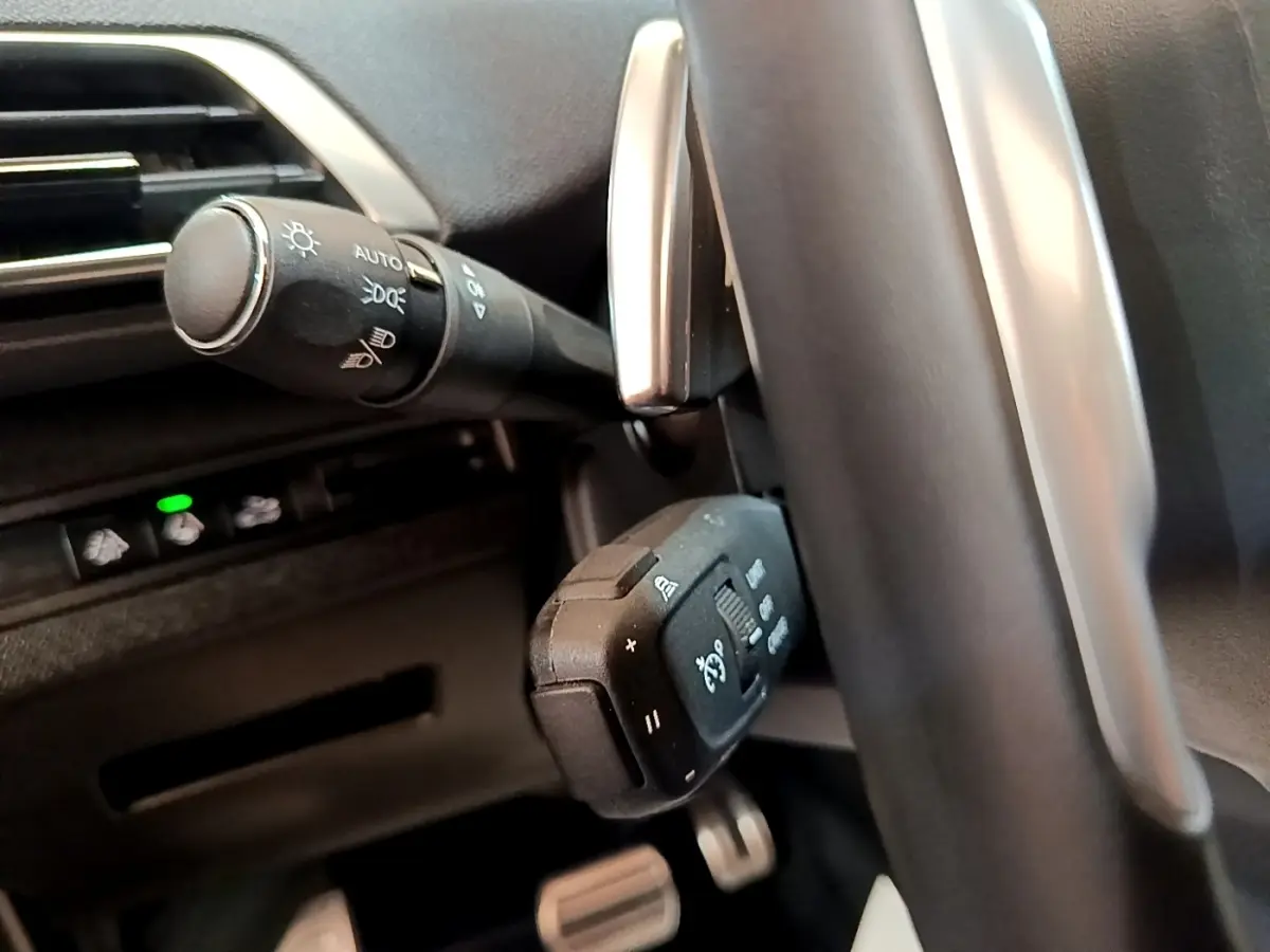 Gros plan sur les commandes au volant en cuir et alu du Peugeot 3008 GT Pack noir, avec boutons multifonctions visibles.