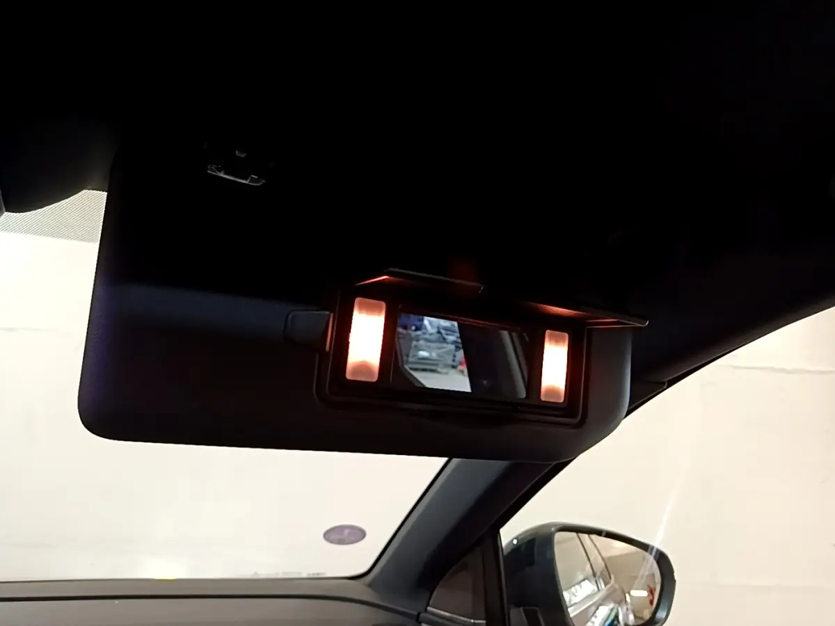 Détail du miroir de courtoisie éclairé sur le pare-soleil côté conducteur d’un Peugeot 3008 noir, intérieur vue latérale.