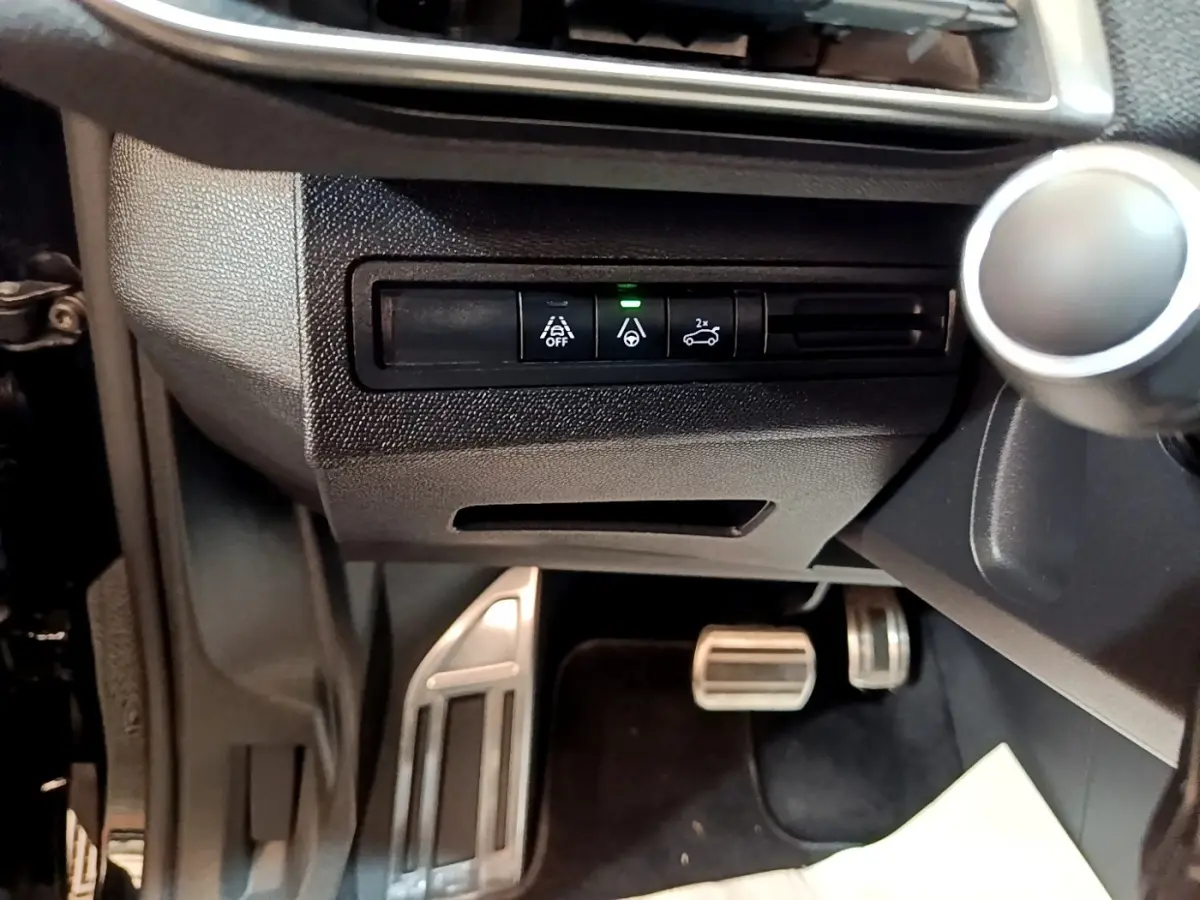 Détail intérieur montrant les commandes d’aide à la conduite et les pédales alu d’un Peugeot 3008 noir, version GT Pack.