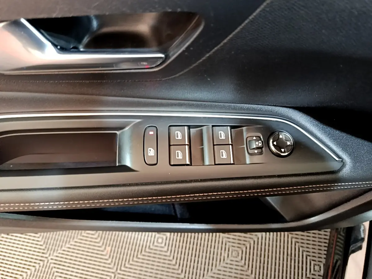 Vue rapprochée du panneau de commandes des vitres côté conducteur d'une Peugeot 3008 noir, avec surpiqûres blanches.