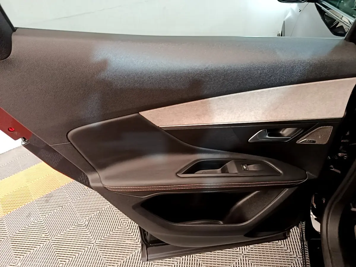 Vue intérieure côté gauche de la porte avant noire du Peugeot 3008 avec habillage cuir et insert tissu clair.