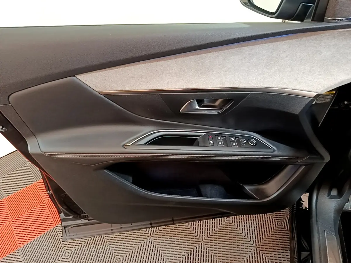Vue intérieure du panneau de porte avant gauche noir du Peugeot 3008 GT Pack 2022 avec commandes électriques et poignée argentée.
