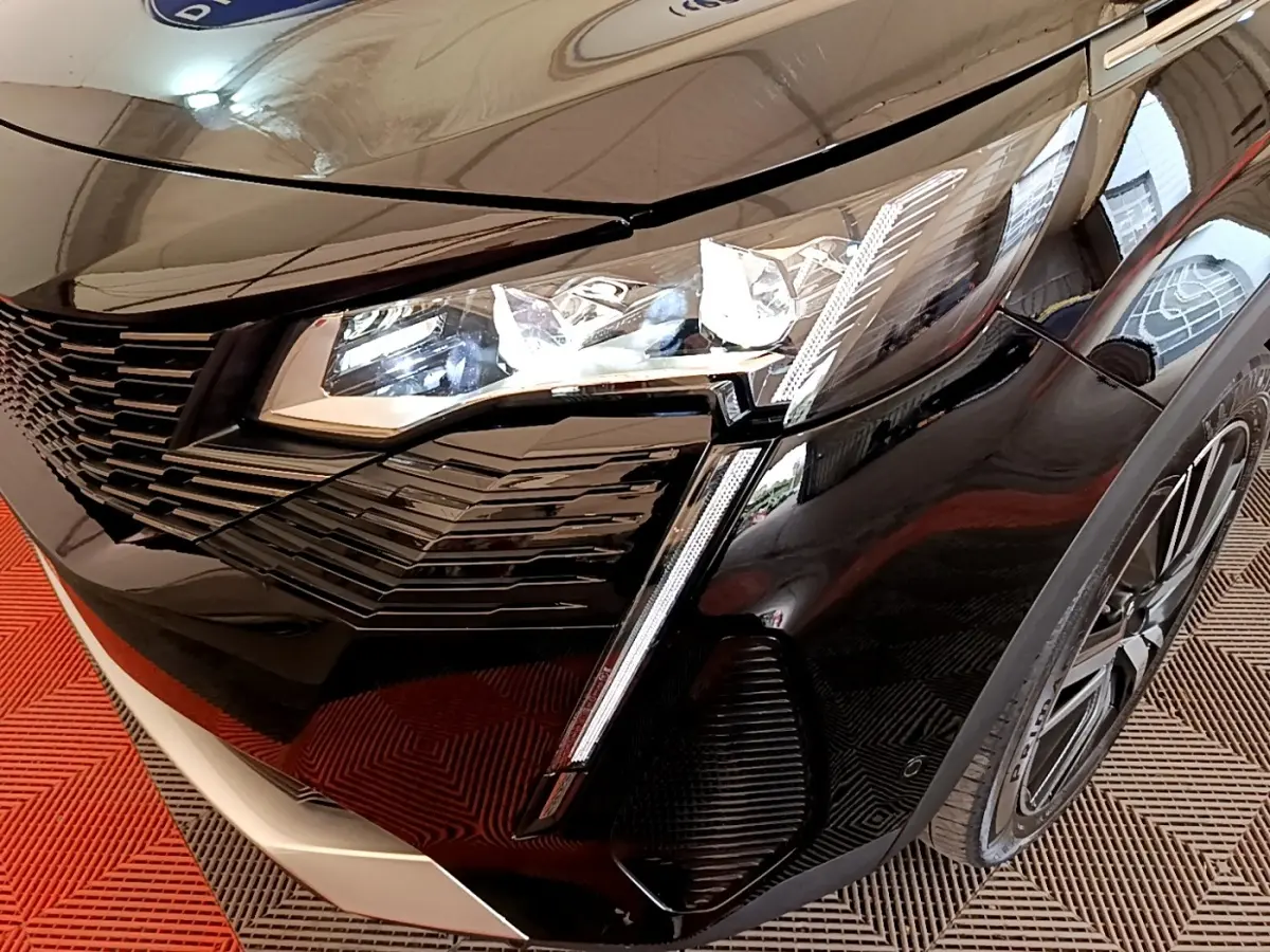 Gros plan sur l'avant droit noir brillant du Peugeot 3008 2022, mettant en valeur le phare LED et la calandre distinctive.