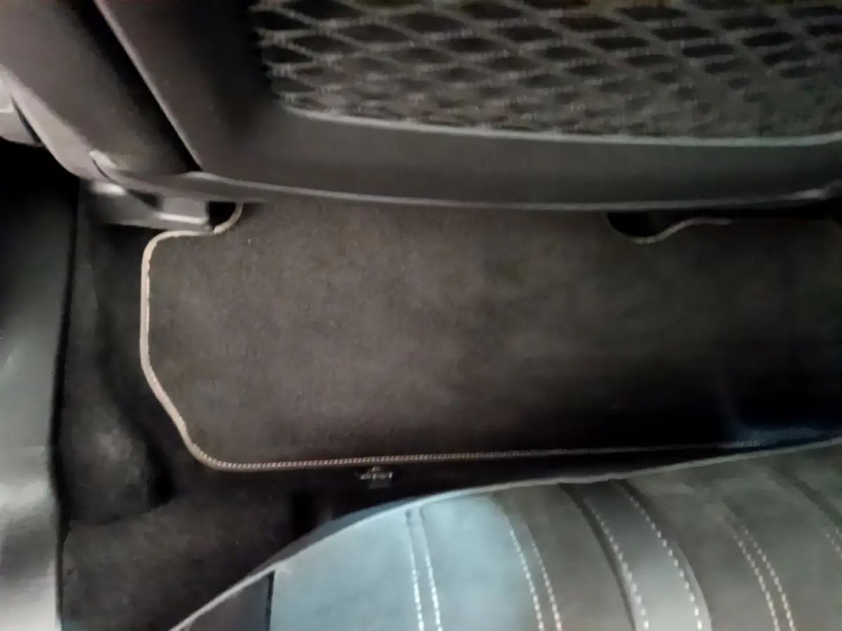 Vue rapprochée du tapis de sol noir et de la partie inférieure d’un siège arrière en cuir dans un Peugeot 3008 noir.