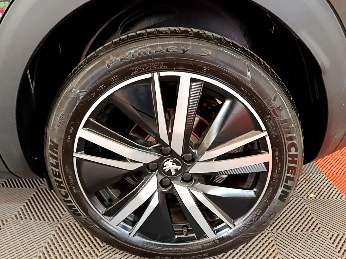 Gros plan sur la roue avant droite noire avec jante alliage bicolore du Peugeot 3008 GT Pack 2022.