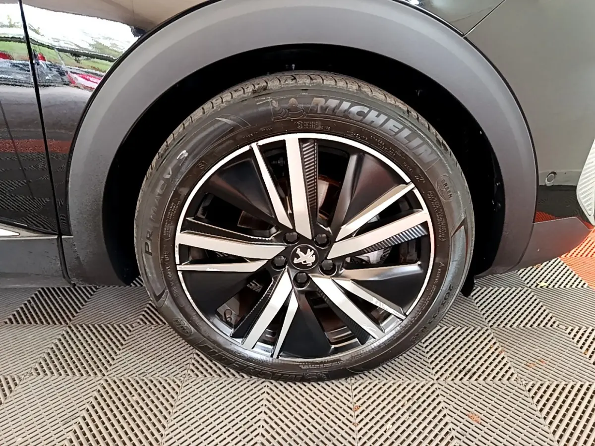 Gros plan sur la roue avant droite noire du Peugeot 3008 2022 avec jante alliage bicolore et pneu Michelin.