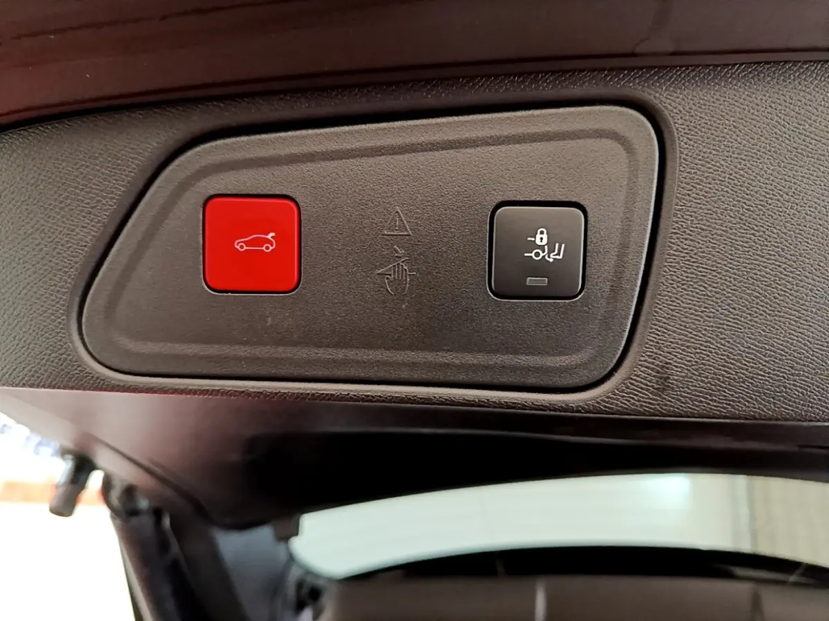 Gros plan sur les boutons d'ouverture et de verrouillage électrique du coffre du Peugeot 3008 noir, vue intérieure arrière.