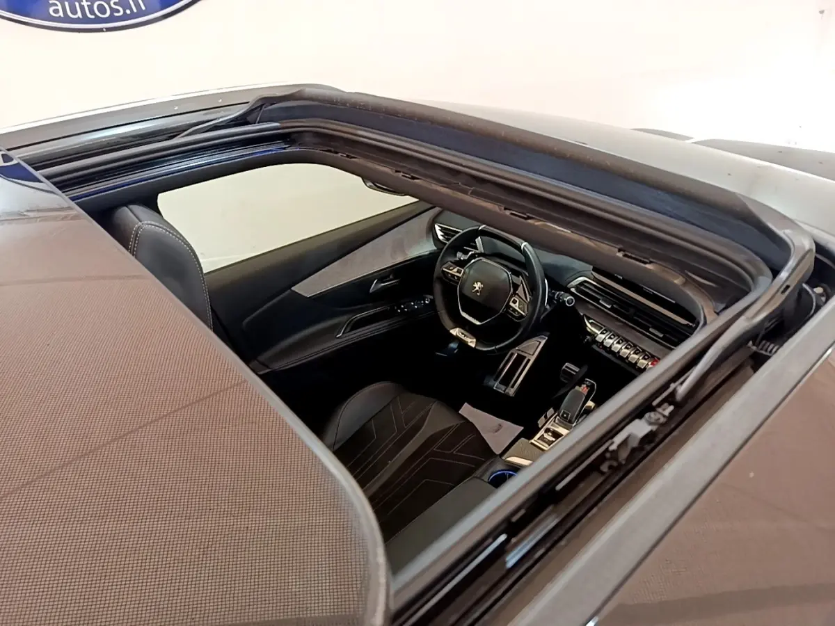 Vue intérieure par le toit ouvrant du Peugeot 3008 noir, mettant en valeur le volant cuir alu multifonctions et la console centrale moderne.