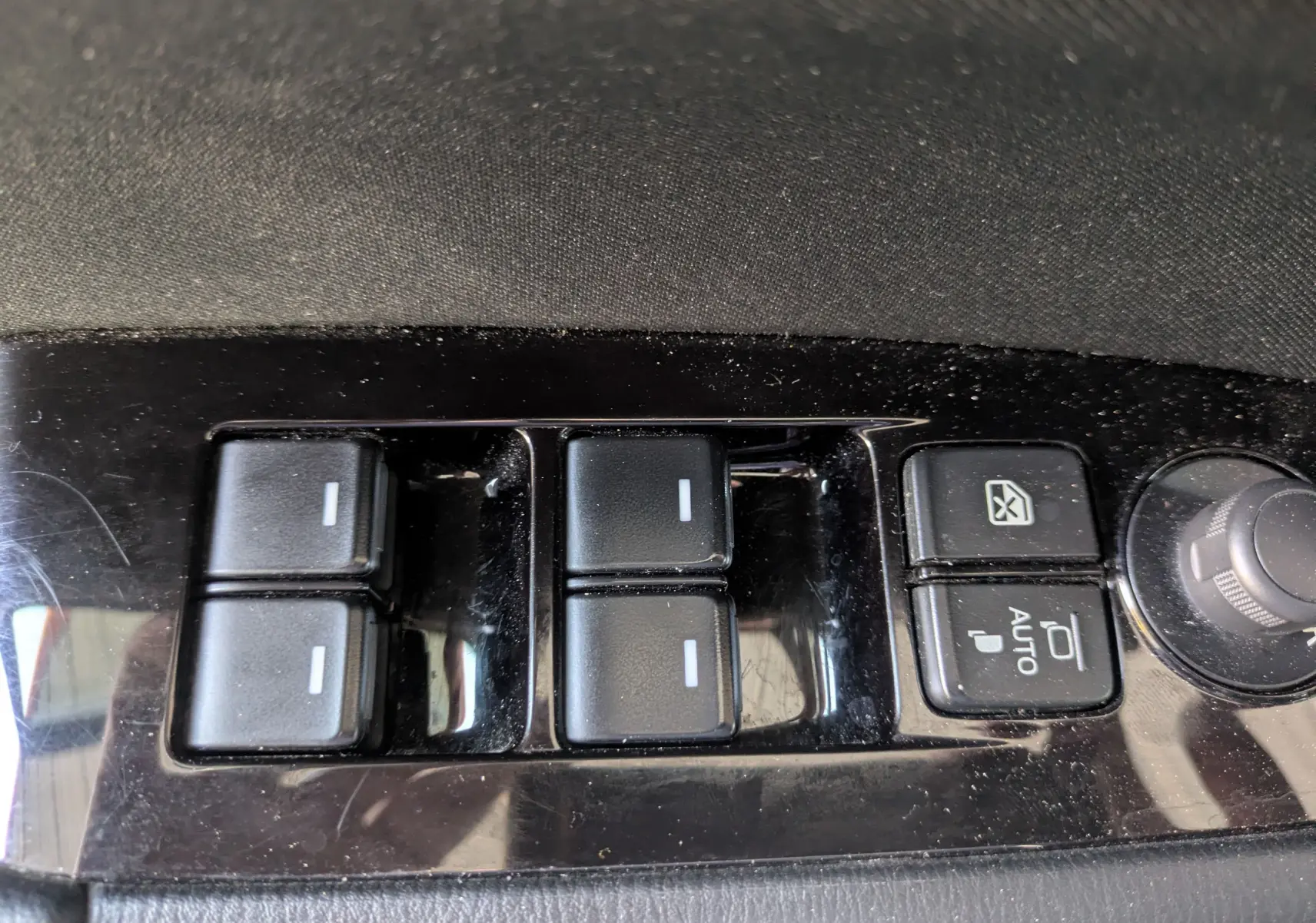 Gros plan sur les commandes des vitres électriques et rétroviseurs d’un Mazda CX-5 gris, version 2020.