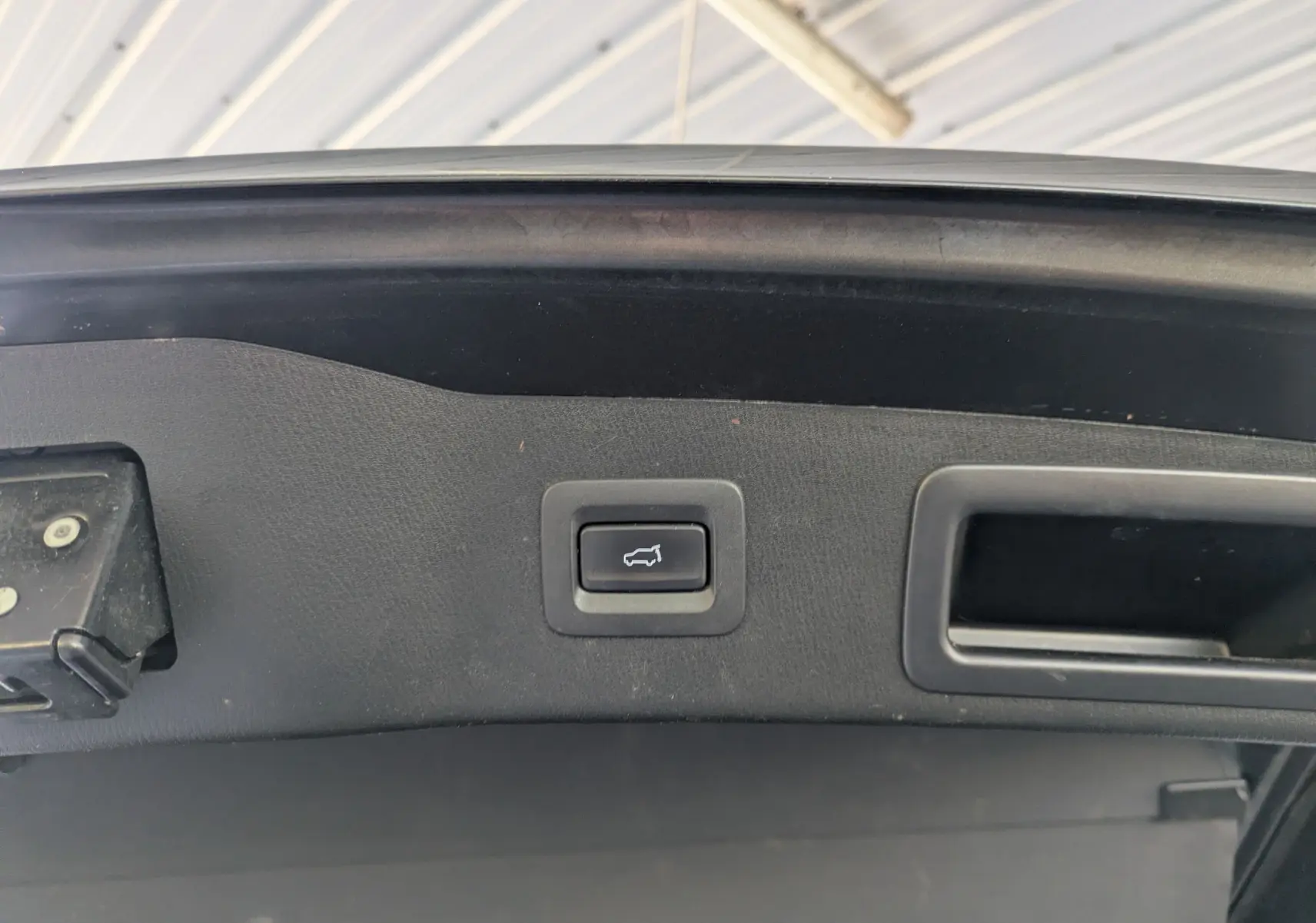 Bouton d'ouverture électrique du coffre sur le hayon intérieur d'un Mazda CX-5 gris 2020.