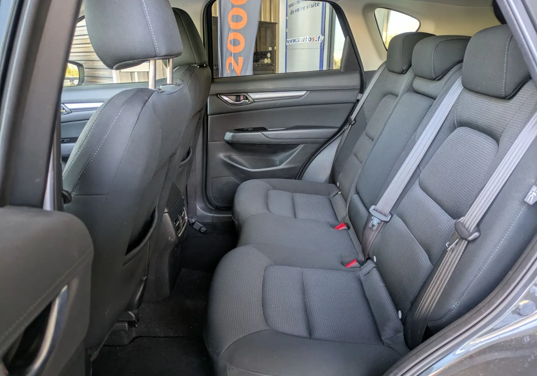 Vue intérieure arrière côté droit du Mazda CX-5 2020 gris, montrant les sièges arrière en tissu noir et les ceintures de sécurité.