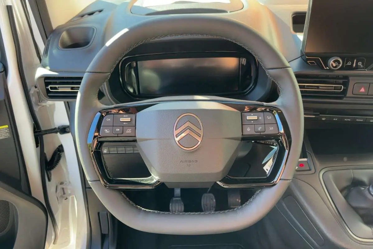 Vue rapprochée du volant cuir multifonctions du Citroën Berlingo Kaolin White avec tableau de bord et écran tactile.