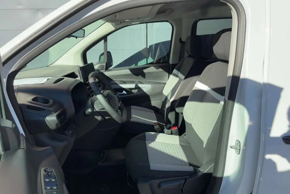 Vue intérieure côté conducteur du Citroën Berlingo Kaolin white 2026, sièges tissu bicolore et tableau de bord moderne.
