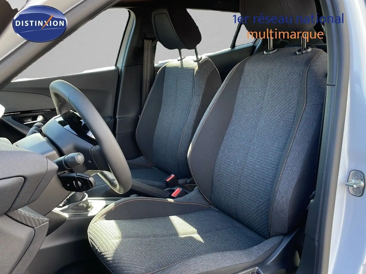 Intérieur du Peugeot 2008 blanc Okenite, vue côté conducteur montrant les sièges tissu noir et gris avec surpiqûres contrastantes.