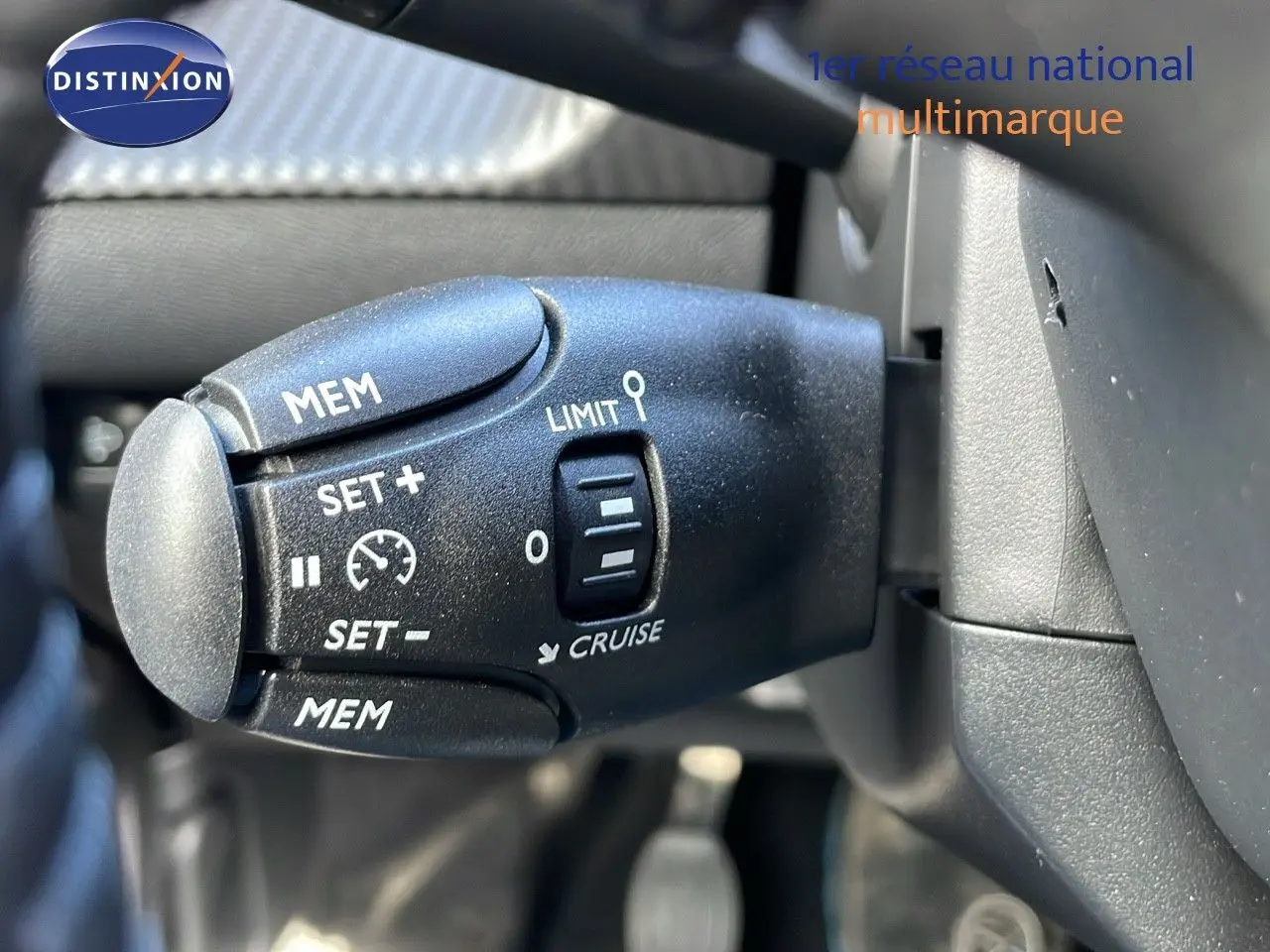 Gros plan sur la commande de régulateur de vitesse du Peugeot 2008 blanc Okenite, côté gauche du volant.