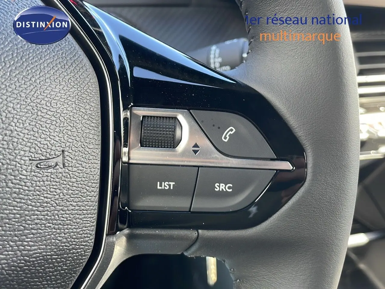 Gros plan sur les commandes gauche du volant en cuir noir du Peugeot 2008 blanc Okenite Metal 2025.