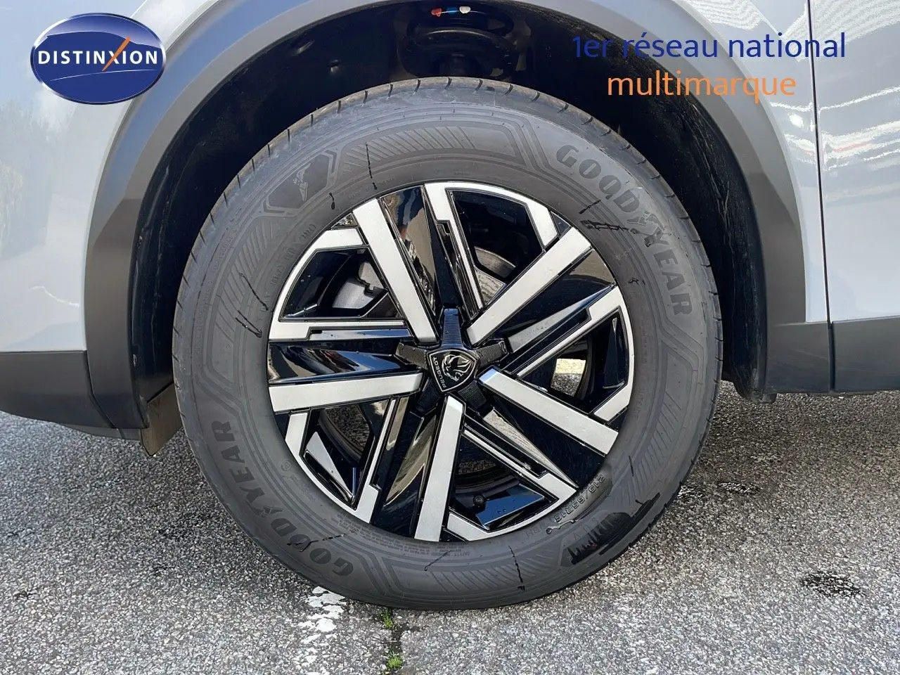 Gros plan sur la roue avant droite d'un Peugeot 2008 blanc Okenite avec jante alliage noire et argentée.