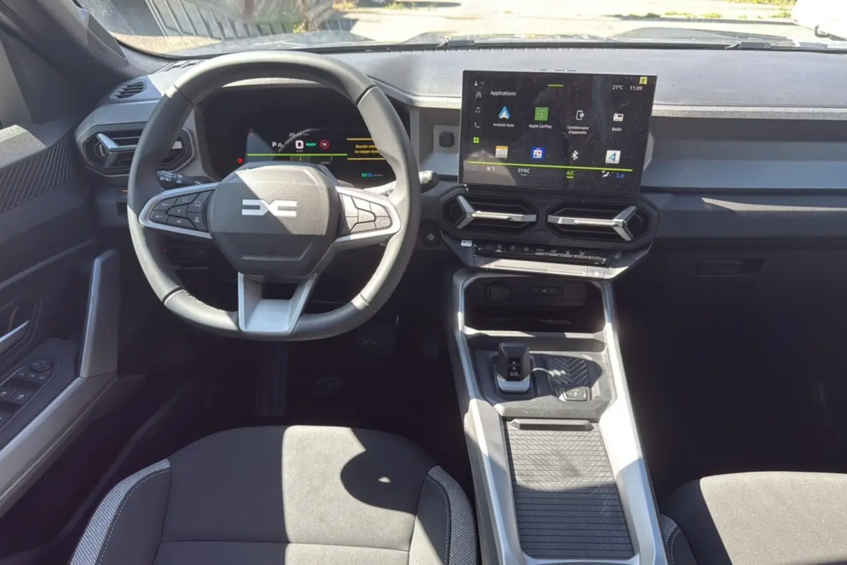 Intérieur du DACIA BIGSTER Hybrid 155 Journey City, vue frontale du poste de conduite avec écran tactile et volant cuir.