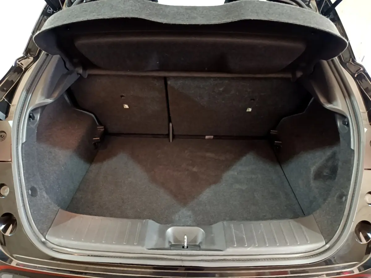 Coffre ouvert vu de l'arrière d'un Nissan Juke Hybrid 143 Business+ noir, montrant l'espace de chargement vide.