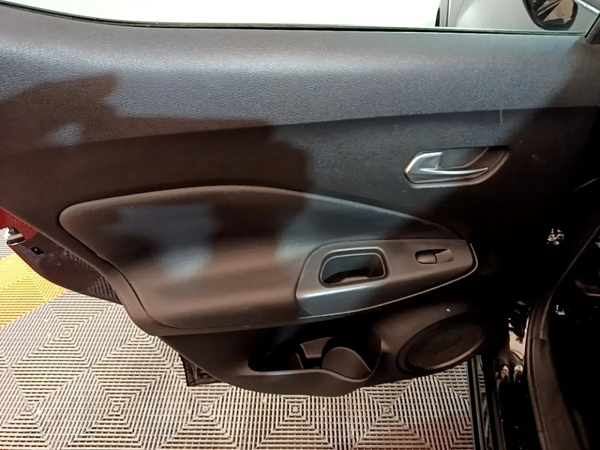 Vue intérieure du panneau de porte côté droit noir du Nissan Juke Hybrid 143 Business+ avec poignée et commande de fenêtre.