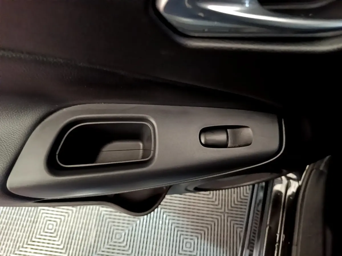 Poignée intérieure de porte côté conducteur du Nissan Juke Hybrid 2022 noire, avec commande de verrouillage intégrée.