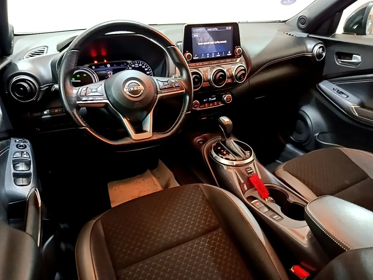 Intérieur noir du Nissan Juke Hybrid 2022 vu côté conducteur, avec volant multifonctions et écran tactile central.