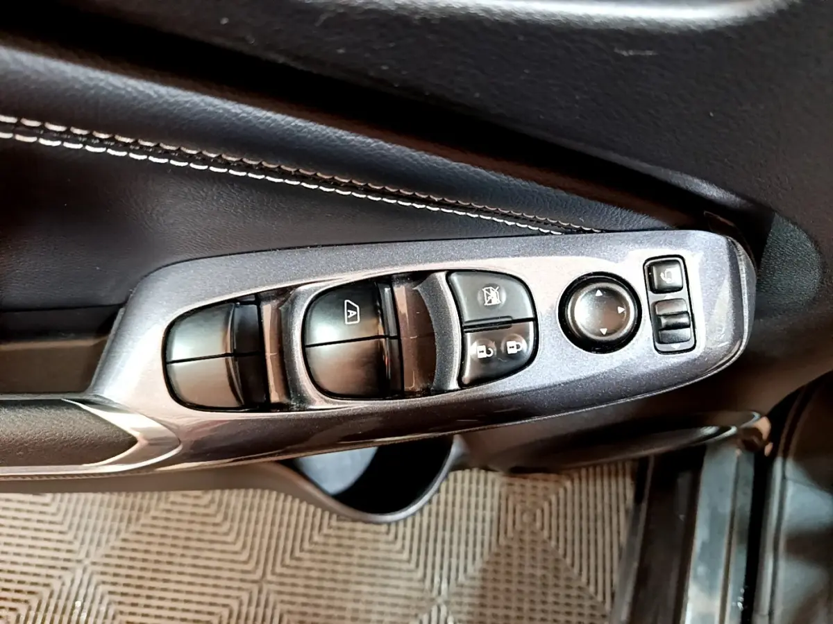 Gros plan sur les commandes de vitres et rétroviseurs côté conducteur du Nissan Juke Hybrid noir de 2022.