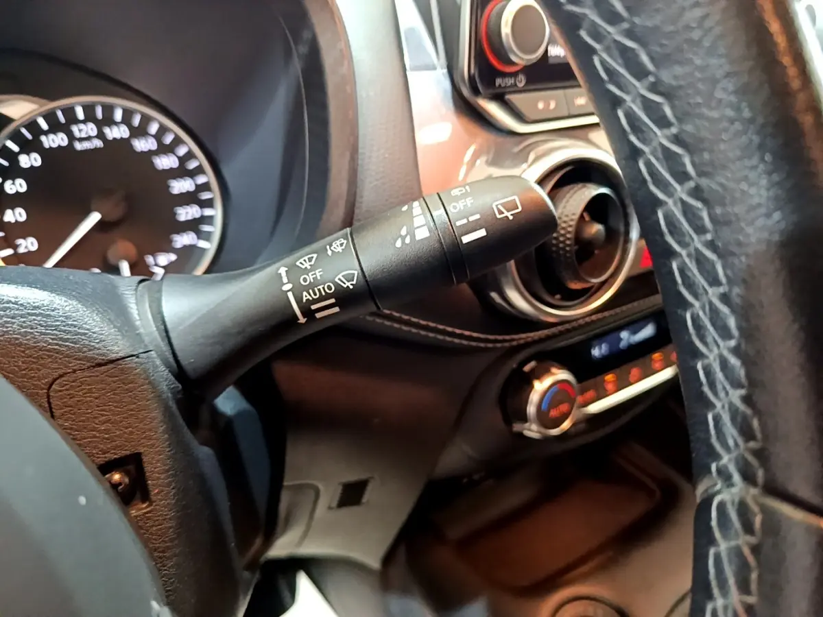 Gros plan intérieur sur le commodo d’essuie-glace et partie du tableau de bord du Nissan Juke Hybrid noir, côté conducteur.